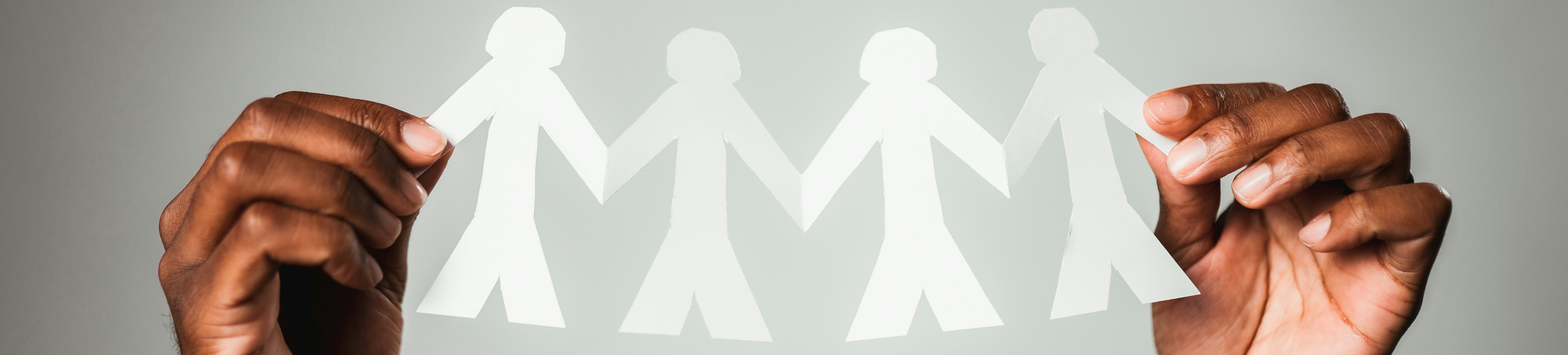 Hands holding paper cut out people